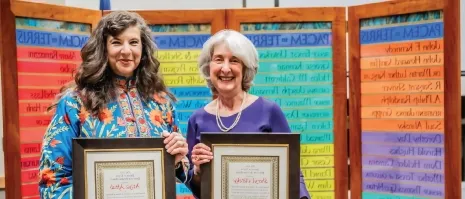 Two women holding up awards 和 smiling.